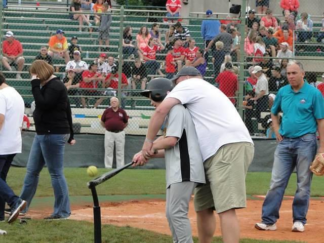 Coach Smith helping Samuel bat.