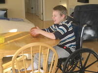 Samuel playing ball at the table.  He likes not having to chase the ball while he is in the wheelchair!